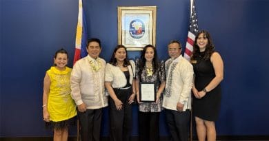 Group photo at the Philippine Honorary Consulate in Chandler, Arizona. Honorary Consul Jenny Lynn Ho-Vijungco stands at the center holding her appointment certificate, joined by dignitaries and guests with Philippine and U.S. flags displayed behind them.