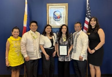 Group photo at the Philippine Honorary Consulate in Chandler, Arizona. Honorary Consul Jenny Lynn Ho-Vijungco stands at the center holding her appointment certificate, joined by dignitaries and guests with Philippine and U.S. flags displayed behind them.